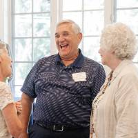 Paul Leidig laughing in conversation with two other women at event